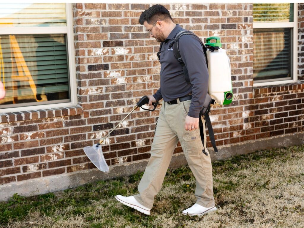 Preferred Pest Management technician performing ant control treatment on a residential home in Plano, TX
