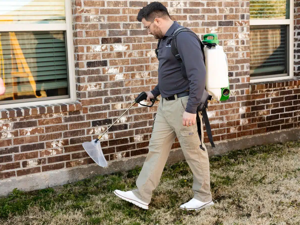 Preferred Pest Management technician performing exterior cockroach treatment at a Plano TX home